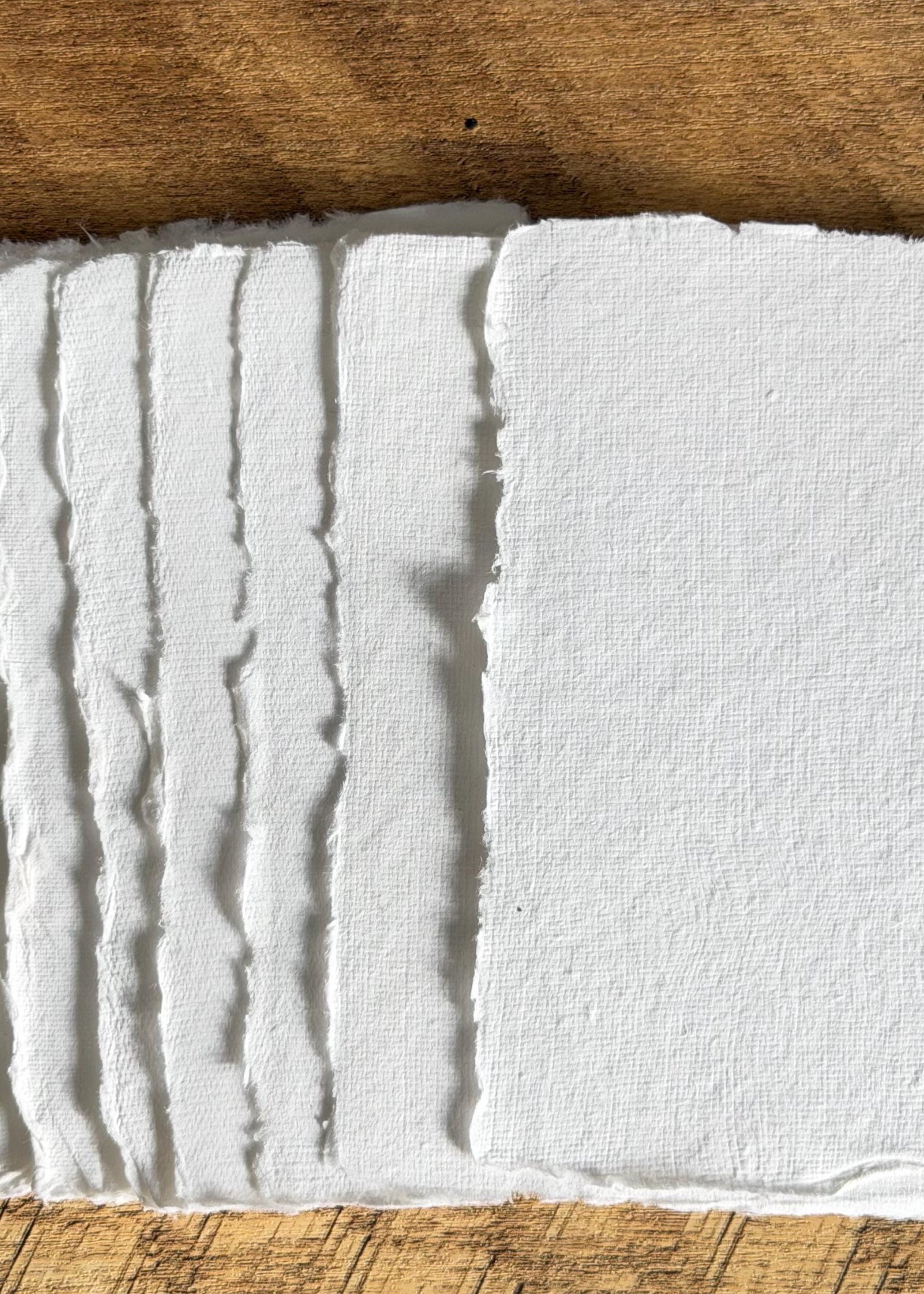 Sheet of cotton paper with textured surface and deckled edges on a wooden background