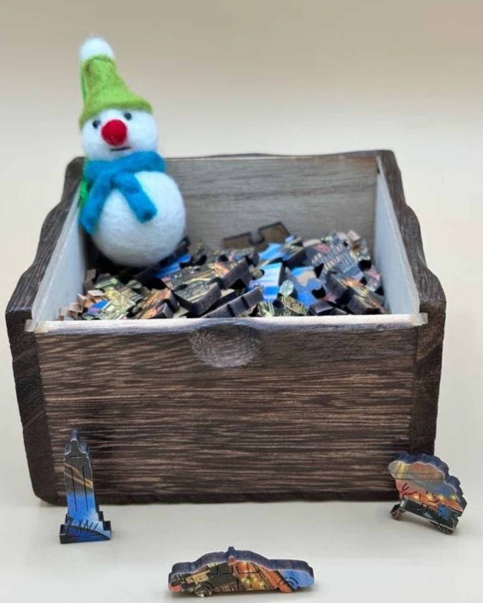 Wooden box with a snowman toy and travel-themed cutouts on a white background